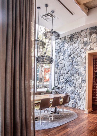 Cultured Stone Echo Ridge Dressed Fieldstone gray thin stone on interior wall with table in chairs in the foreground