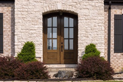 Glen-Gery | Limestone Cashmere building stone veneer on exterior of home entry with brick, black window shutters, and wood double front door