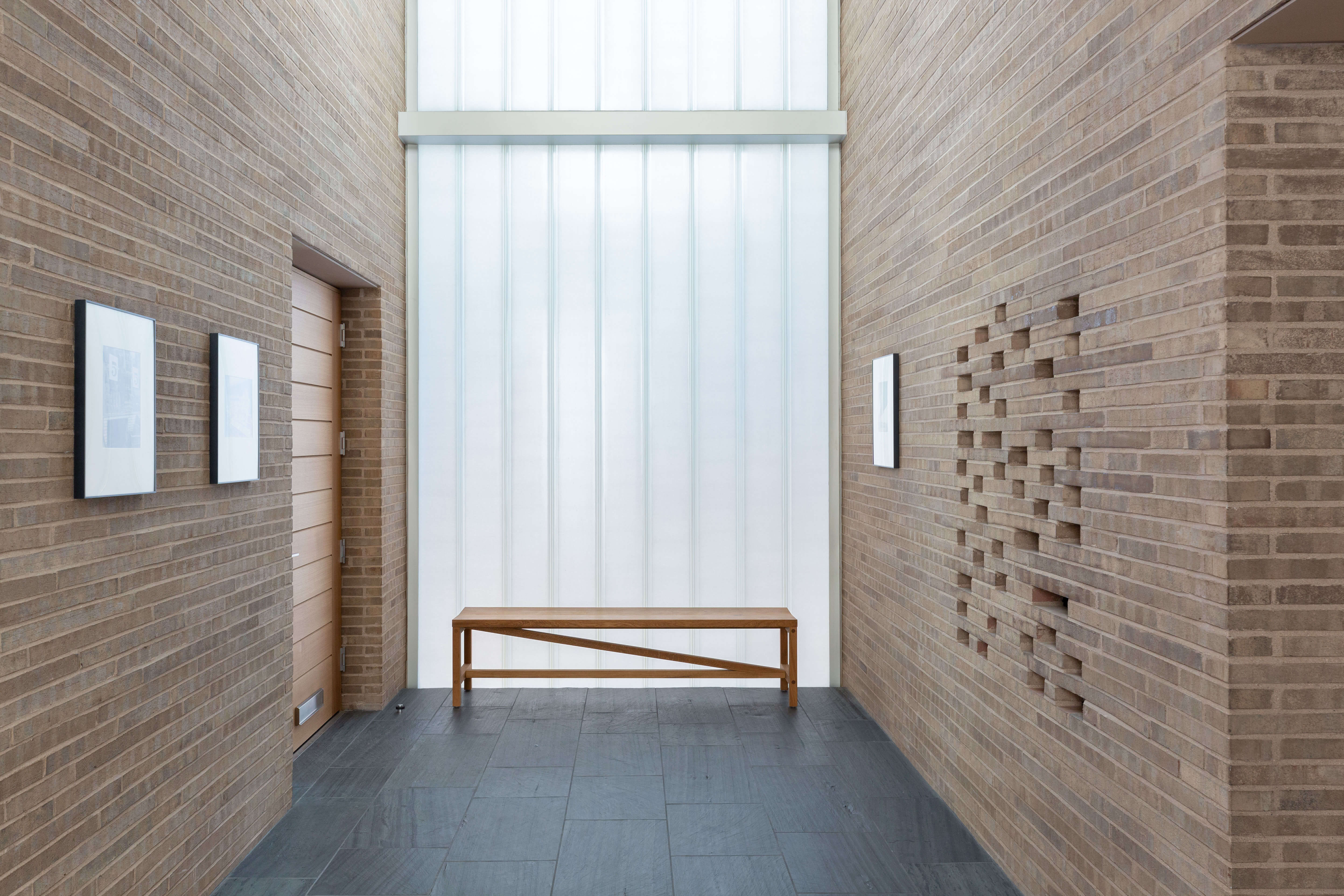 Interior brick walls with large vertical window and a bench