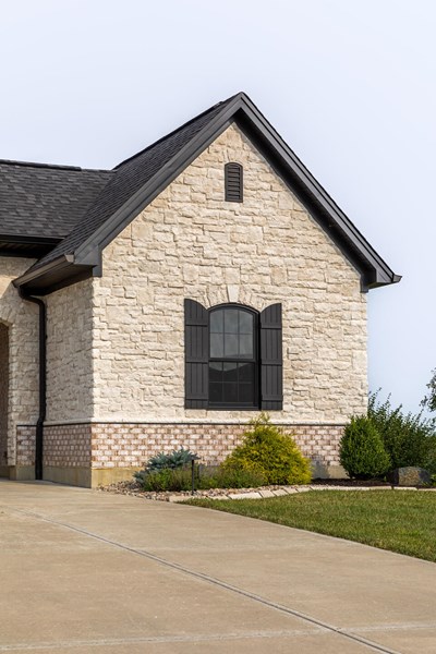 Glen-Gery | Limestone Cashmere building stone veneer on exterior of home with brick and black window shutters