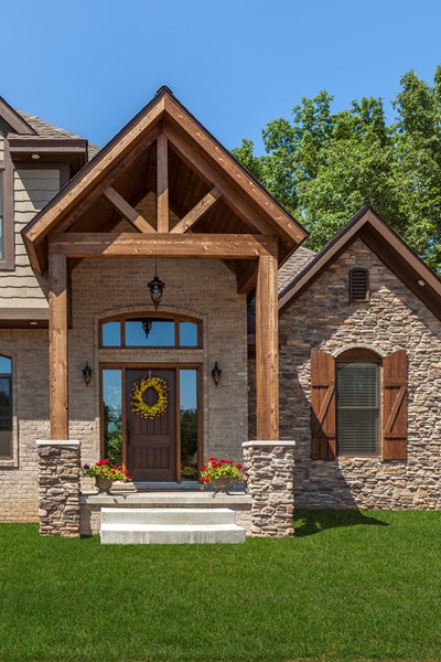 Glen-Gery | Ledgestone Buckingham tan and gray building stone veneer on exterior of home with tan brick, front door, and heavy timber framed entry