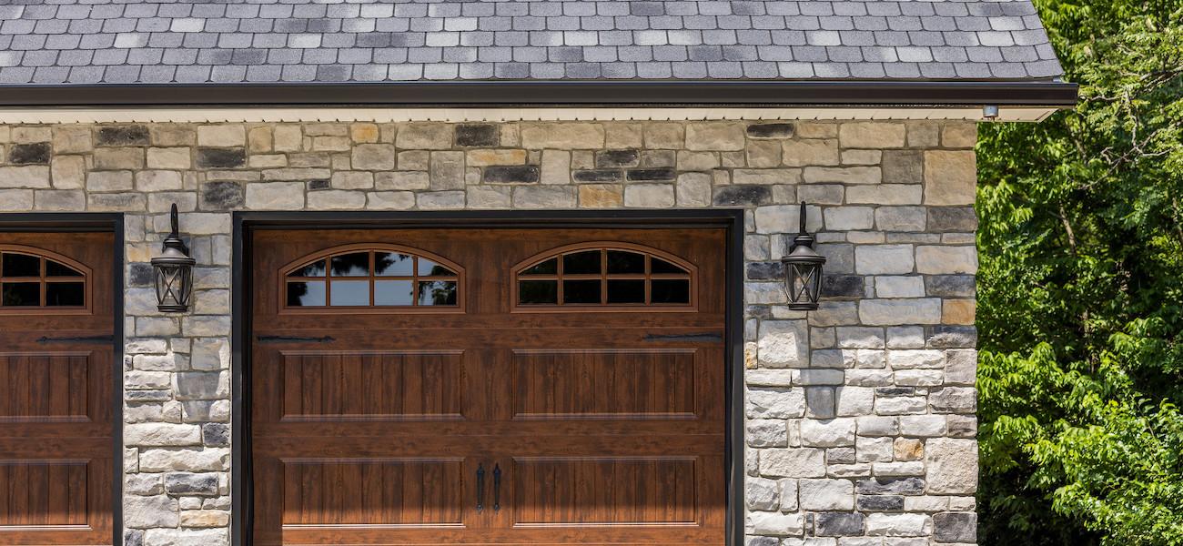 Glen-Gery | Limestone Kentucky Grey building stone veneer on homes garage with wooden garage doors and coach lights